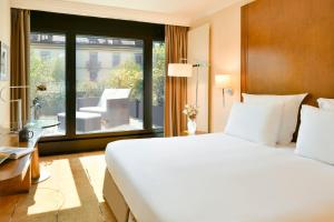 日内瓦日内瓦沃里克酒店的卧室设有一张白色大床和大窗户