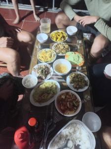 河江Homestay Hoàng Vũ的一群人坐在餐桌旁,吃着各种食物