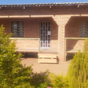 卡萨内Sunshinevibe guest house的砖砌建筑,设有两扇窗户和两把长椅