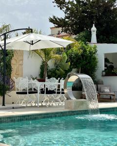 卢斯Palm View Guesthouse, adults only的一个带遮阳伞和喷泉的游泳池