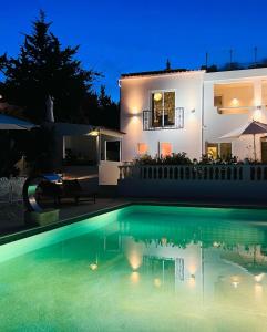 卢斯Palm View Guesthouse, adults only的夜间在房子前面的游泳池
