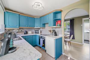 纽尼顿BridgeCity Cheerful 3 bedroom home in Nuneaton的厨房配有蓝色橱柜和桌子