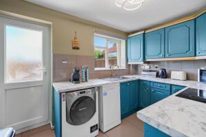 纽尼顿BridgeCity Cheerful 3 bedroom home in Nuneaton的厨房配有蓝色橱柜和洗衣机。