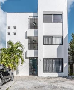 坎昆Pako Stays - Luxurious & Spacious 2 Bedroom Apartments Close to the Beach, Free Wi-Fi, Ideal Location in Downtown Cancun Centro的前面有棕榈树的白色房子