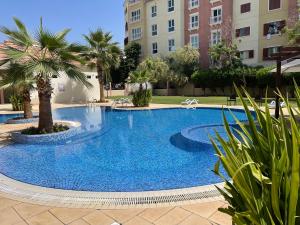 迪拜Birchfort - Newly renovated unique 1 bedroom apartment的一座种植了棕榈树和建筑的大型蓝色游泳池
