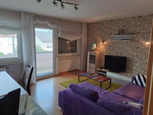 皮特林根Ferienwohnung Schleiten的客厅配有紫色沙发和砖墙