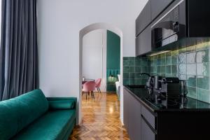 克拉科夫Wawel Boutique Residence - Krakow Old Town的一间带绿色沙发的客厅和一间厨房