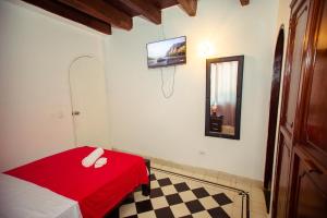卡塔赫纳Casa Hotel Marbella Beach的一间设有红色床和墙上电视的房间