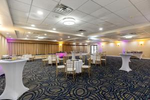 马纳萨斯马纳萨斯温德姆花园酒店的宴会厅配有白色桌椅和紫色照明