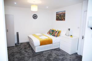 哈罗Stunning 2-Bed Apartment in Harrow的白色的卧室配有一张床和墙上的时钟