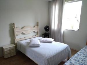 贝洛奥里藏特Casa verde的卧室配有白色的床和窗户。