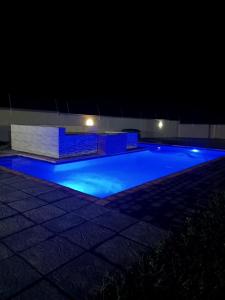 MʼBazwaneHeavenly Towers的夜间游泳池,拥有蓝色照明