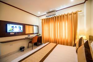 万荣Vang Vieng Freedom Star's Hotel的一间卧室配有一张床、一张书桌和一台电视。