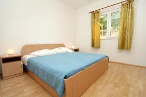 莫鲁纳特Apartments by the sea Molunat, Dubrovnik - 8956的一间卧室配有一张带蓝色毯子的床和窗户。