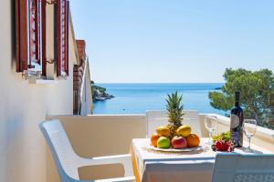 格鲁达Apartments and rooms by the sea Molunat, Dubrovnik - 9102的一张桌子,上面放着一盘水果和一瓶葡萄酒