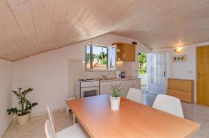 格鲁达Apartments and rooms by the sea Molunat, Dubrovnik - 9102的厨房配有木桌和白色椅子