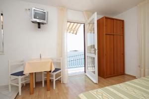 格鲁达Apartments and rooms by the sea Molunat, Dubrovnik - 9102的一间带桌子和电视的卧室以及一个阳台