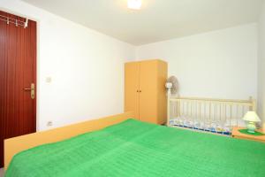 布拉托Apartment Prigradica 9141b的一间卧室配有一张绿色的床和一张婴儿床。