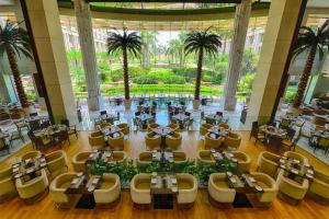 新德里新德里酒店的一间设有桌椅的餐厅,种植了棕榈树