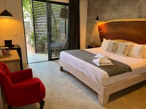 图卢姆Little Gem Hotel Tulum La Veleta的一间卧室配有一张床和一张红色椅子
