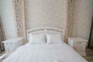 利沃夫Апартаменти з 2-ма ізольованими спальнями і балконом в центрі Львова的一张带白色枕头的白色床和2个床头柜