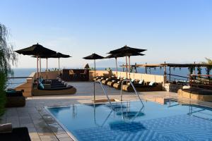 卡普里卡普里滨海别墅酒店的度假村内带椅子和遮阳伞的游泳池