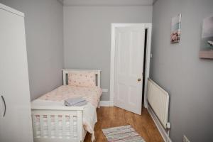 邓巴顿Bonhill Getaway的一间白色的小卧室,房间内设有一张小床