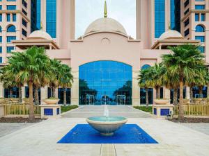 阿布扎比Rixos Marina Abu Dhabi的棕榈树建筑前的喷泉