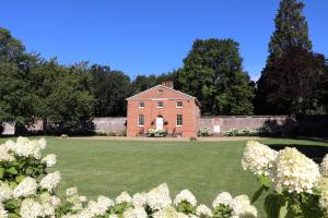 赫特福德The Walled Garden at Woodhall Estate的一座古老的砖房,拥有白色花卉的大院子