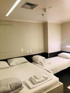 坎皮纳斯Hotel Aero Sleep Campinas的配有白色床单的客房内的两张床