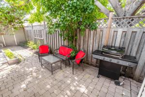 多伦多Cozy 5 Bedroom House in Downtown Toronto by GLOBALSTAY的一个带椅子、烧烤架和围栏的庭院