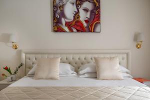 博洛尼亚Hotel Re Enzo的卧室配有一张白色床,墙上挂有绘画作品
