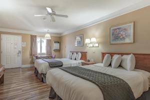 BurneyShasta Pines Motel & Suites的酒店客房配有两张床和吊扇。