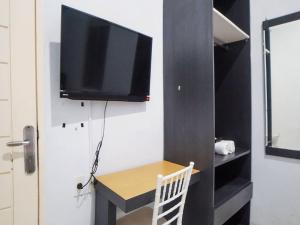 棉兰SUPER OYO 91627 Wika Wiki Homestay的客房设有书桌和墙上的电视