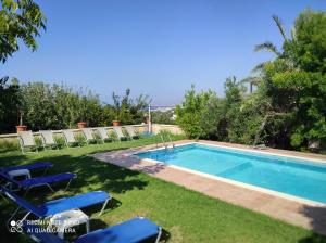 达拉索Villa Koulouridi的院子里的游泳池周围设有椅子