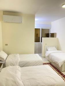 瓦迪穆萨Rose city inn的配有白色床单的客房内的两张床