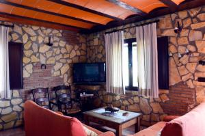 CarcabueyCasa Rural El Tejar Viejo的客厅设有石墙和电视。