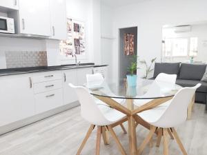 圣玛丽亚港Apartamento Marina el Puerto的白色的厨房配有玻璃桌和白色椅子