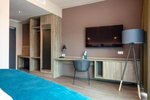 柏林附近贝尔瑙H24 Stadthotel Bernau的一间卧室配有电视和桌椅