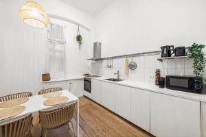 维也纳The BoHo Loft VIE的厨房配有白色橱柜和桌椅