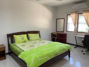 Ban Thalat Choeng ThaleH&Q 1BR Cozy House, Bangtao Beach的一间卧室配有一张带绿色棉被的床和一张书桌