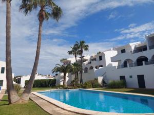 桑帕克Apartamento Son Parc Menorca的一座楼前棕榈树游泳池