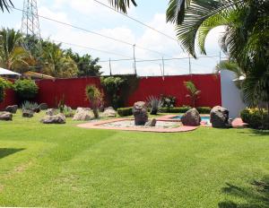 Emiliano ZapataPreciosa Casa Palmera en Cuernavaca con Alberca, Wifi, TV y Cocina Para fin de semana, descanso, vacaciones o Home office的一个带岩石和红色围栏的花园