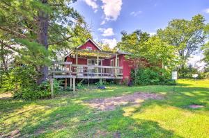 Charming Farm Cottage with Fire Pit and Grill!的一座红色的房子,在院子里设有一个大甲板