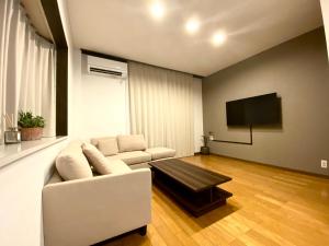 伊势市外宮前別邸　星凪庵的客厅配有白色沙发和平面电视。