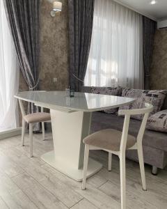 库斯塔奈Однокомнатная студия, центр的一张白色的桌子和椅子,位于一个配有床的房间
