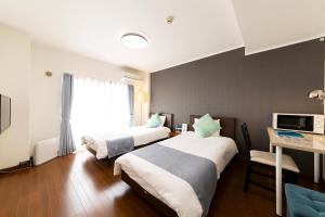 福冈机场住宿公寓式酒店的酒店客房设有两张床、一张桌子和一台电视。