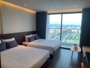 绥和市Win Condotel Apec Phú Yên的酒店客房设有两张床和大窗户。