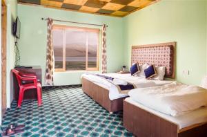 Karzok GömpaTsomoriri Hotel Lake View的一间卧室配有两张床和红色椅子