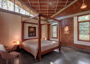 西达普尔Estate Stay - Riverside Coffee的卧室配有一张位于砖墙的天蓬床